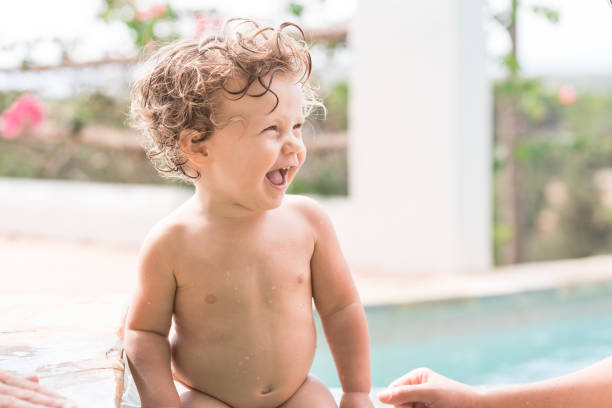 Blonde baby girl of 15 months outdoor at the pool laughing and having fun
