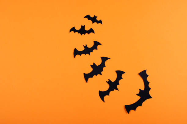 istock Flock of paper bats on orange wall. 1060834012