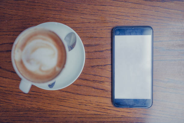 istock Close-Up Of Coffee By Mobile Phone On Table in cafe 1060834774