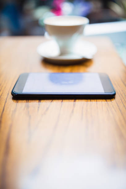 istock Close-Up Of Coffee By Mobile Phone On Table in cafe 1060834782