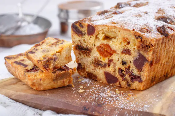 Traditional Christmas cake with fruits and nuts on white table.