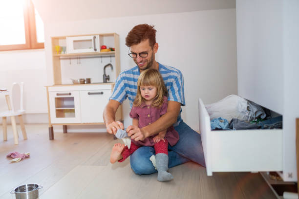 Dad is helping toddler daughter to get dressed