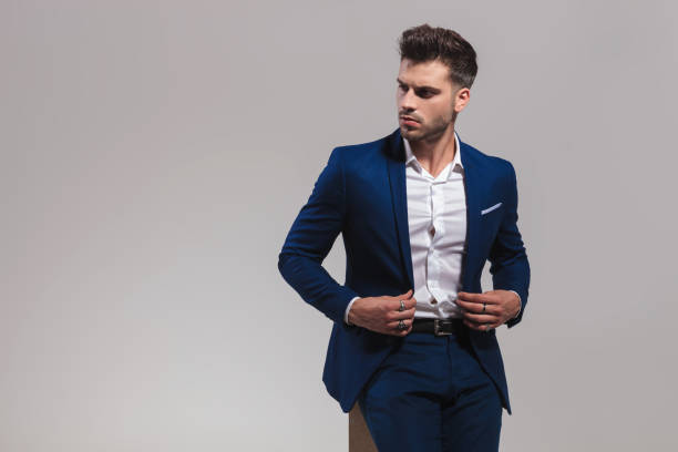istock elegant man buttoning his coat while sitting on wood box 1060842866