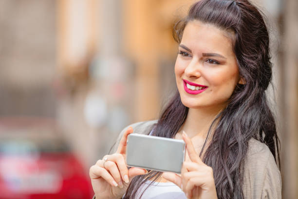 Cute young woman using cellphone in urban surroundings.