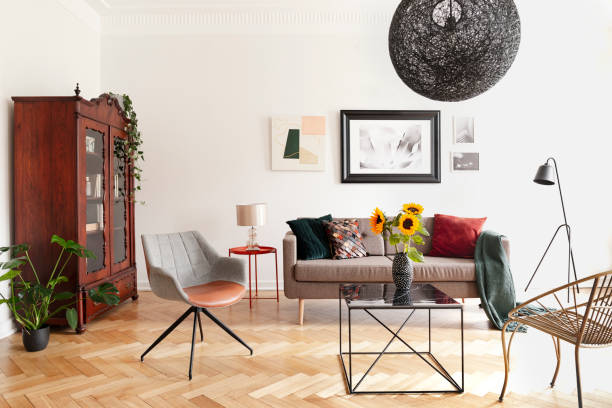 istock Sunflowers on table between armchairs in white flat interior with posters above sofa. Real photo 1060850196