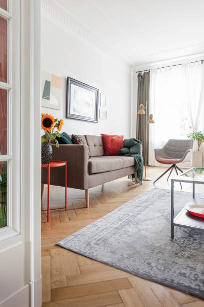 istock Sunflowers on table next to settee in bright flat interior with posters and grey armchair. Real photo 1060850198