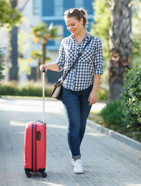 istock Girl carrying suitcase by streets 1060855494