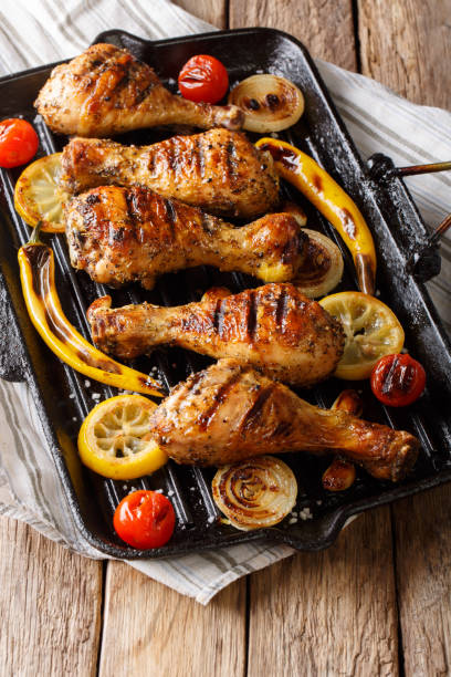 istock Delicious food: grilled chicken drumstick legs with vegetables in a grill pan close-up on a table. vertical, rustic 1060858848