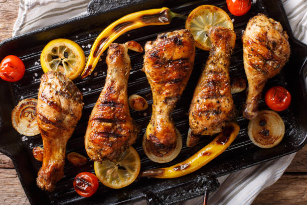 istock Delicious food: grilled chicken drumstick legs with vegetables in a grill pan close-up on a table. horizontal top view, rustic 1060858914