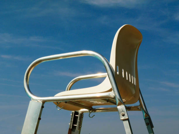 empty aluminum life guard high chair at swimming pool in the summer under blue sky
