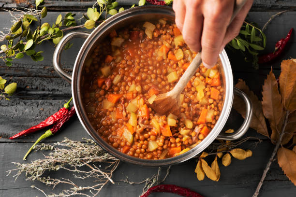 uomo che prepara uno stufato vegetariano di lenticchie - mescolare foto e immagini stock