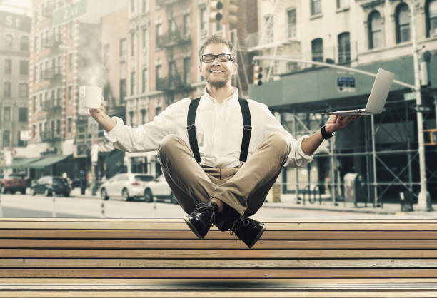 Young man is soaring in the air Young man is soaring in the air with a Cup of coffee and a laptop levitation stock pictures, royalty-free photos & images