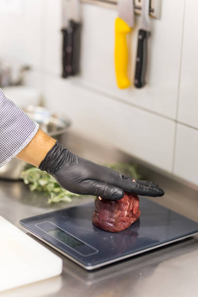 Cook Measuring the Weight of Beef Steak on a Kitchen Counter