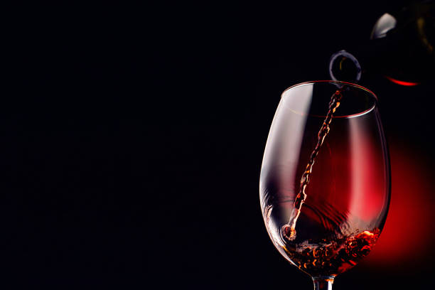In the glass is poured liquid on a black background with a red spot. Left area for text