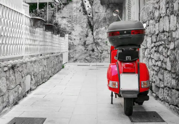 Photo of Red scooter parked on the empty street.