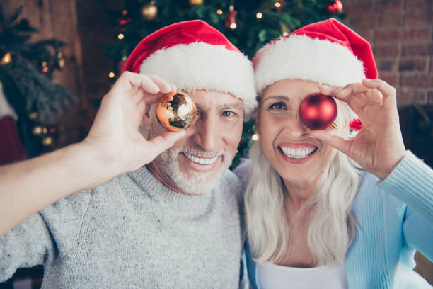 istock Closeup portrait of two charming adorable playful ecstatic grey-haired married spouses holding round toys covering closing one eye playful mood in house 1060867626