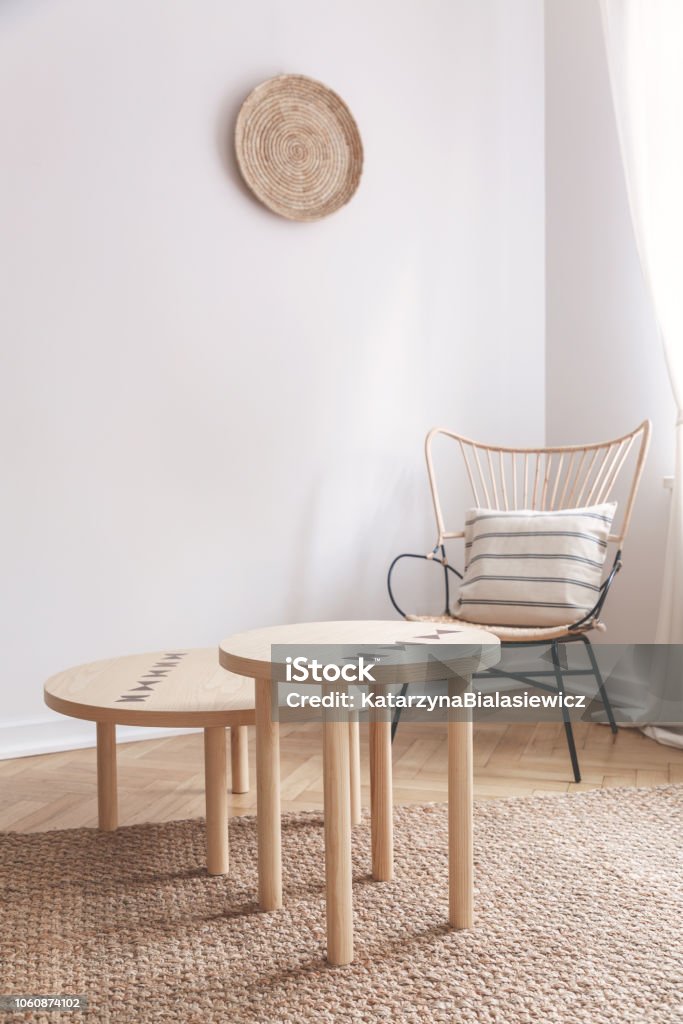 Two Small Coffee Tables And Wicker Chair With Pillow On It In