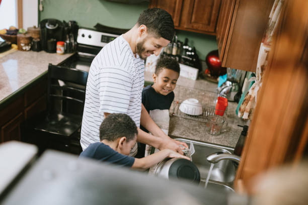 istock Father Washes Dishes in Kitchen With His Sons 1060877136