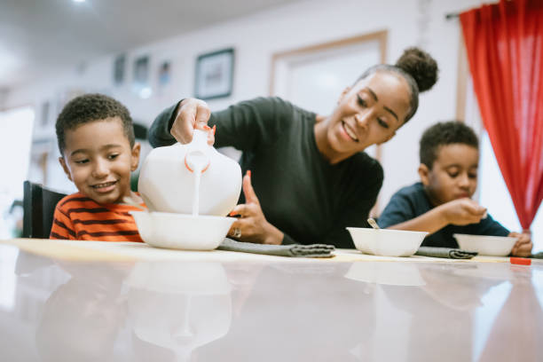 madre che sta colazione con i suoi due ragazzi - eating women breakfast cereal foto e immagini stock