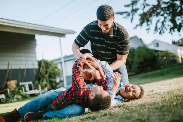 Photo of Father Plays Football Outside With His Sons