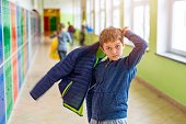 Child boy dressing his autumn jacket in school