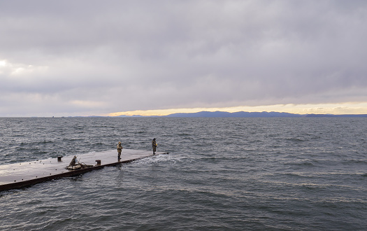 VLADIVOSTOK, RUSSIA - OCTOBER 28, 2018: Two fishermen are fishing on the pier.