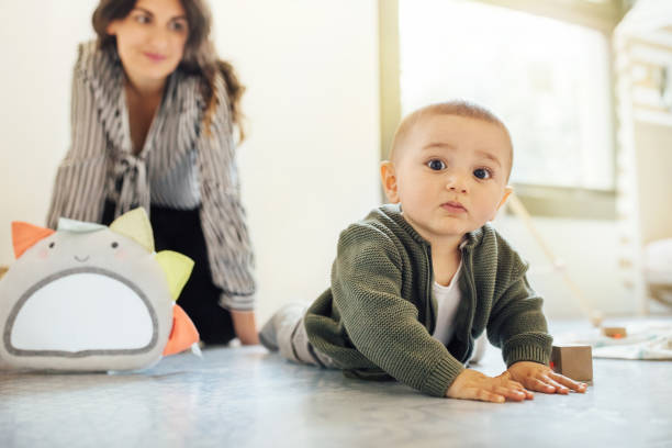 istock Cute little boy crawling on floor with mother at back 1060893442