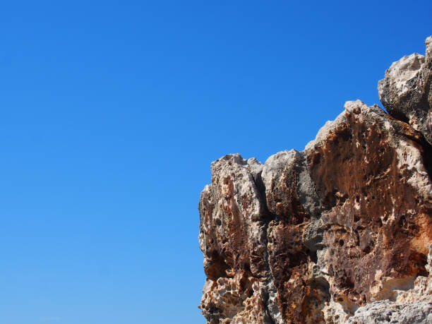 a rough jagged rocky outcrop against a bright blue sunlit sky