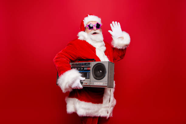 ¡bienvenido! perfil de vista positivo abuelo edad madurados gafas estrella santa de sombrero del traje de la tradición mantener vintage jugador agitando hola hola adiós aislado noel invierno diciembre rojo fondo - retro christmas audio fotografías e imágenes de stock