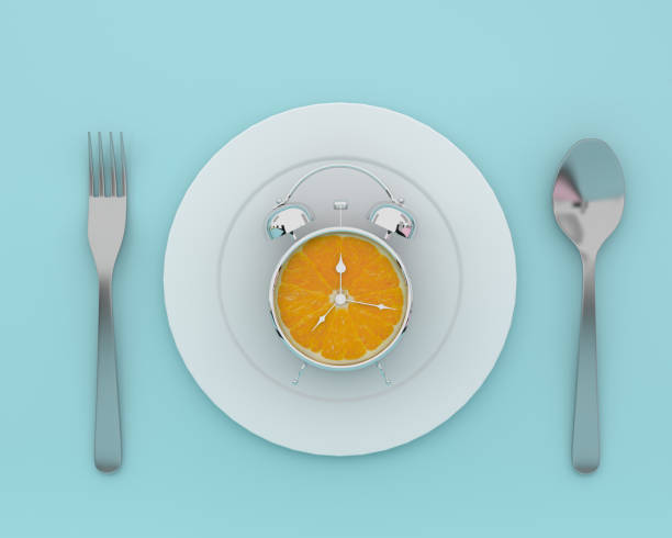 kreatywny układ pomysłu wykonany ze świeżego pomarańczowego plasterka budzika na talerzu z łyżkami i widelcami na niebieskim tle. minimalnej koncepcji opieki zdrowotnej. - clock time alarm clock orange zdjęcia i obrazy z banku zdjęć
