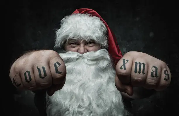 Photo of Funny Santa Claus showing fists with love xmas tattoo