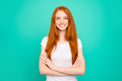 Portrait of nice glad cheerful positive peaceful cute bright vivid shiny red straight-haired girl in casual white t-shirt, folded hands, isolated over turquoise green background