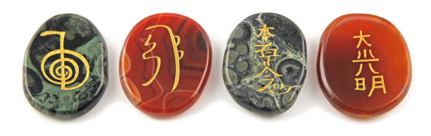 The four major Reiki Healing Symbols etched into palm stones made of Carnelian and Kambaba Jasper placed in a neat row against a white background reiki stock pictures, royalty-free photos & images