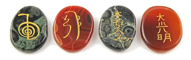 etched into palm stones made of Carnelian and Kambaba Jasper placed in a neat row against a white background