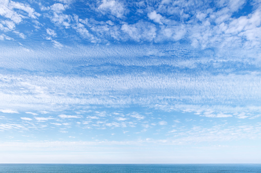 Beautiful blue sky over the sea with translucent, white, Cirrus clouds. The horizon line