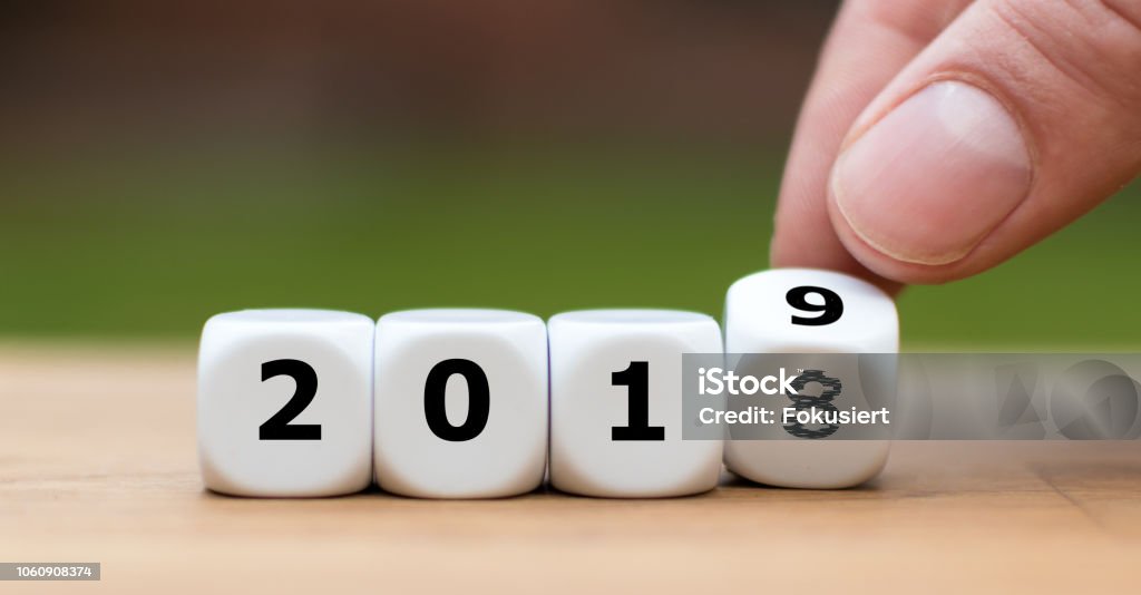 Hand is turning a dice and symbolically changes the year 2018 to 2019 Examining Stock Photo