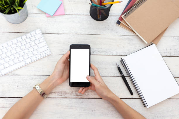 istock hand woman using a telephone, empty screen smart phone and computer on wooden table In home office. with clipping path 1060918236