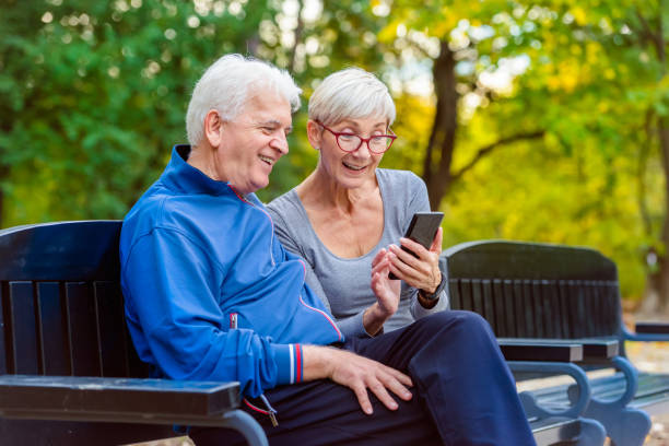 istock Senior couple sitting on the bench in the park using smart phone 1060927140