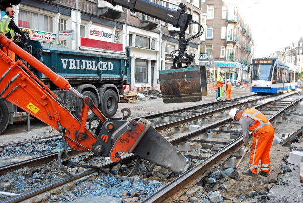 Rail track maintenance workers inspect and repair tram and railway tracks using a mechanical excavator. The Amsterdam Tram is the largest tram network in the Netherlands and one of the largest in Europe. Therefore urban transport infrastructure requires constant maintenance and renewal.