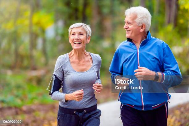 Coppia Senior Sorridente Che Fa Jogging Nel Parco - Fotografie stock e altre immagini di Terza età - Terza età, Esercizio fisico, Salute