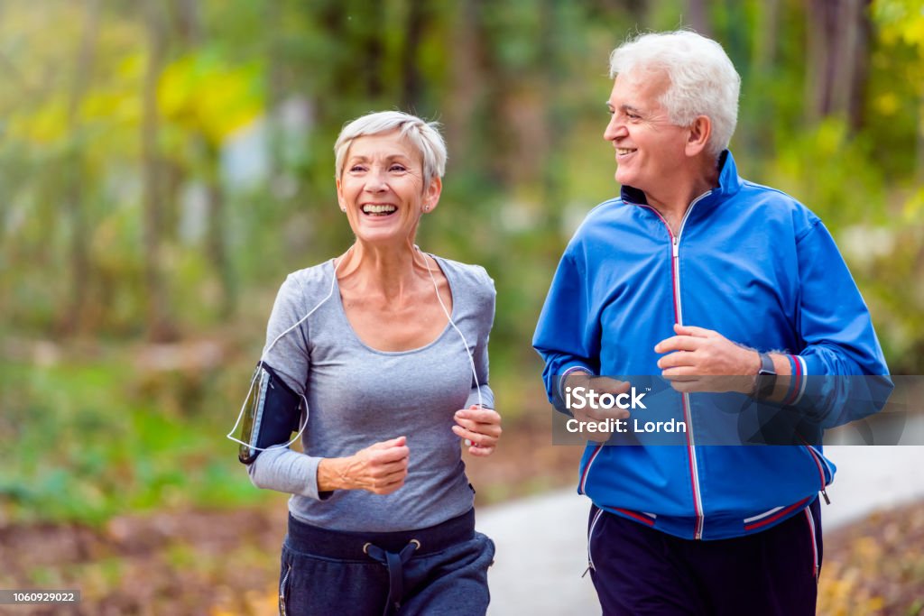 Smiling senior couple jogging in the park Senior active couple running, walking and talking in the park. Healthy lifestyle Senior Adult Stock Photo