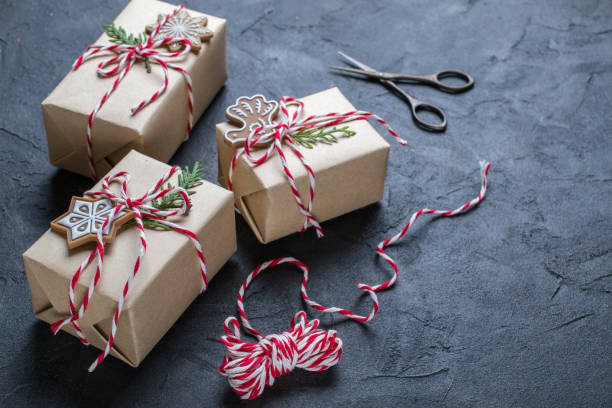 istock Packing Christmas gifts. Christmas gift boxes and decorations, pine branches on dark  table. Present decorated with natural parts Top view with copy space 1060930484