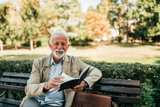 istock Smiling older man reading a book on the bench. 1060937340