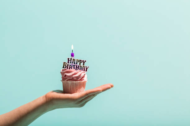 istock Birthday muffin with candle held in woman's hand. 1060939460