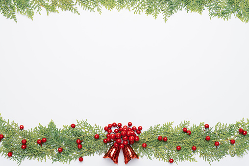 Christmas and New Year's composition. Top view of spruce branches, pine cones, red berries and bell on white background.