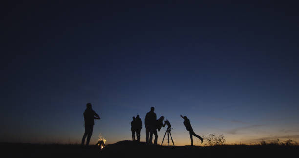istock Friends with campfire looking through telescope in night 1060959296