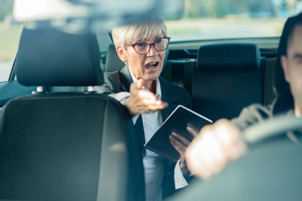 nervous senior female manager riding on a back seat of a car, running late for a meeting - back seat imagens e fotografias de stock