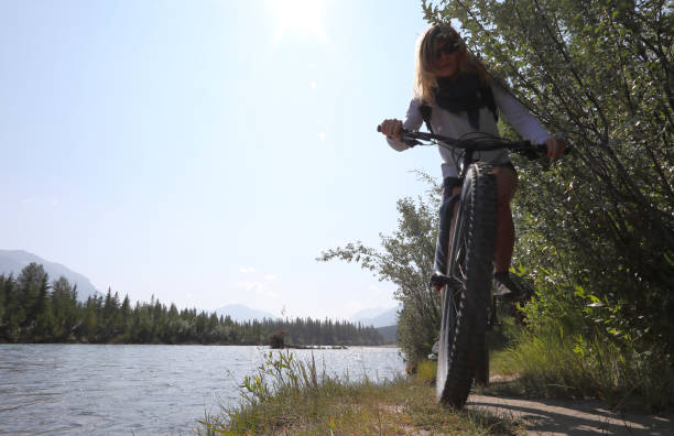 istock Young woman bikes along mountain creek 1060967252