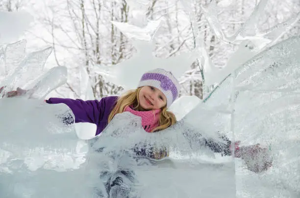 little blond girl with ice sculptures in forest