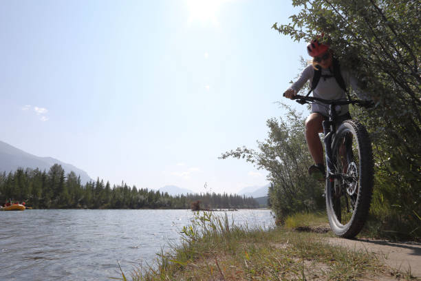 istock Young woman bikes along mountain creek 1060968346